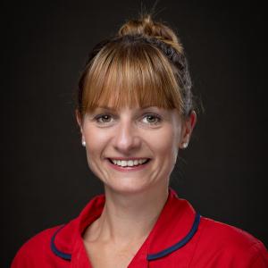 Smiling woman in red uniform with St Michael's Hospice logo.