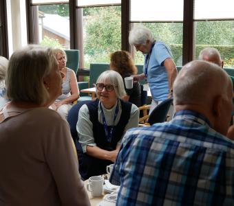 Seniors socializing over coffee in a bright, relaxed setting.