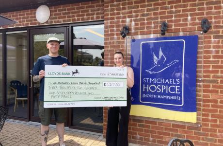 Man and woman hold a large donation check for St. Michael's Hospice.