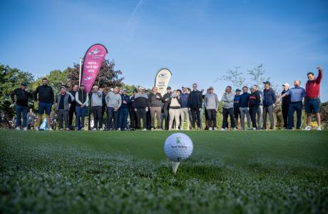 Golfers on charity day with gold flag and hole in foreground