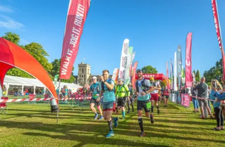 Runners participating in an outdoor race with colorful flags and a castle in the distance.