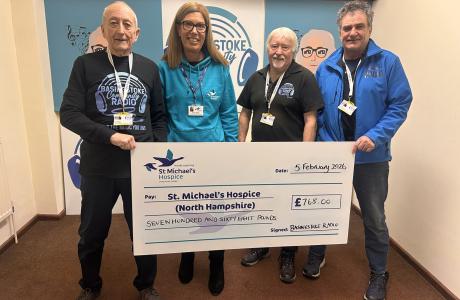 Four smiling adults hold a giant check for St Michael's Hospice.