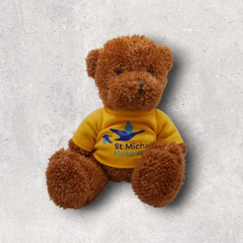 Brown teddy bear in a yellow t-shirt with St Michael's Hospital logo.