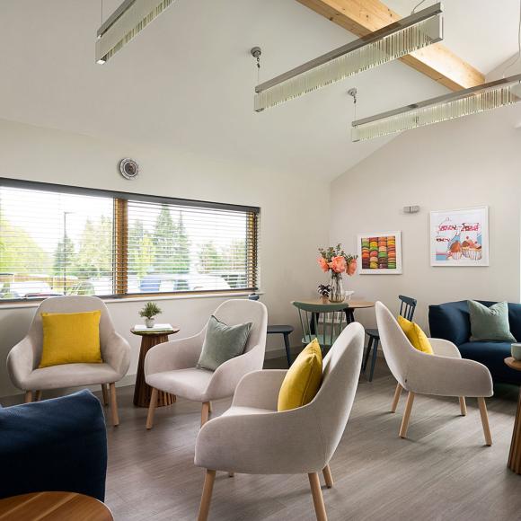 Modern, bright waiting room with cream walls, large windows, and colorful seating.