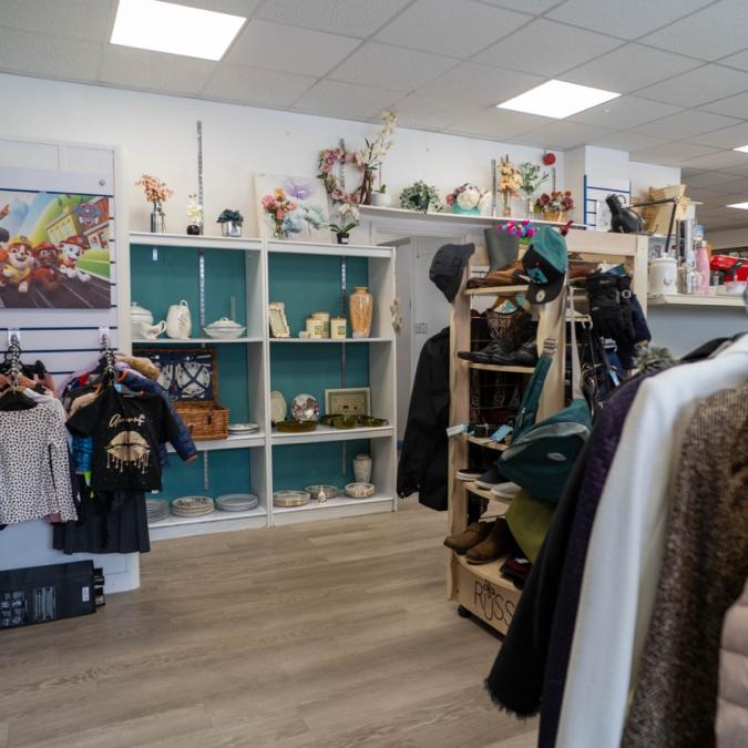 Interior of a small shop with clothes racks and shelves displaying jewellery and decorative items.