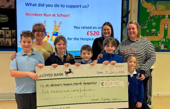 Children and adults present a large £520 donation check from a school fundraiser.