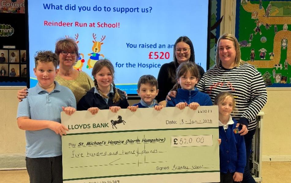 Children and adults present a large £520 donation check from a school fundraiser.