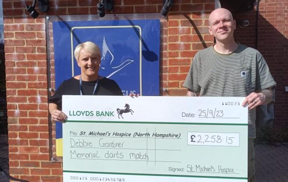 Man and woman standing outside St Michaels hospice holding cheque for £2258.15