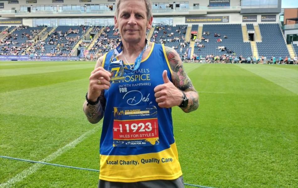 Darren standing in a stadium with a medal having completed a sporting event for st michaels
