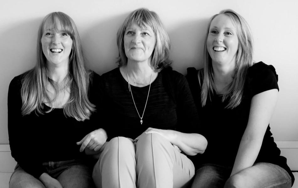 Black and white photograph of a smiling mother and her two daughters.