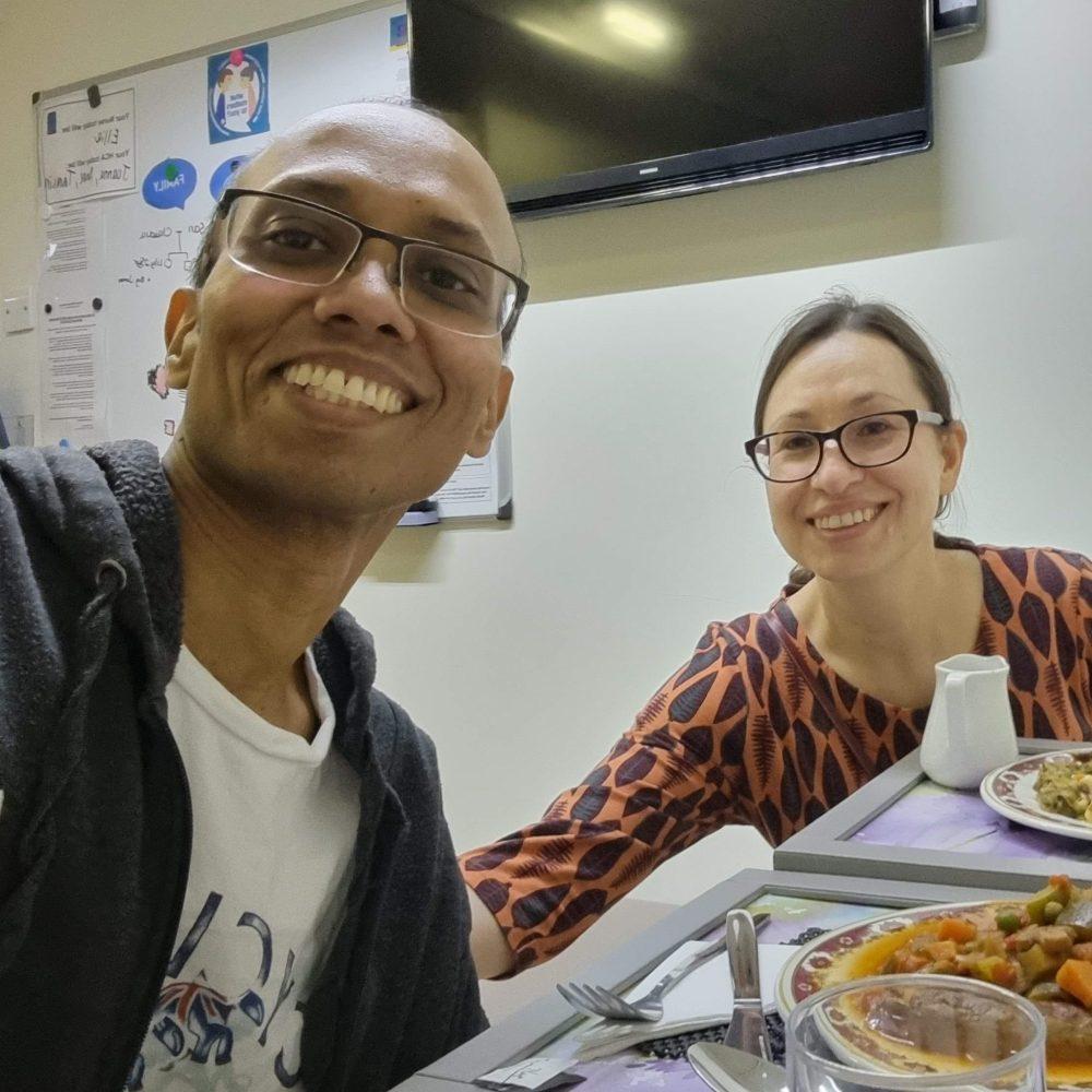Smiling man and woman wearing glasses at a table with food.