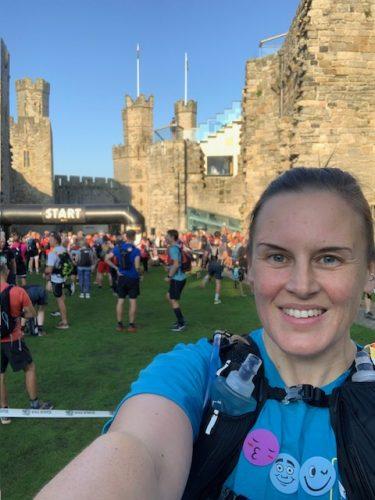 Smiling runner selfie, crowds gathered for a race in front of an ancient castle.