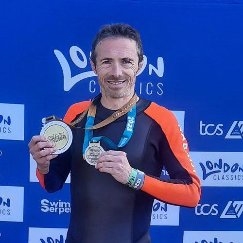 Man in athletic clothes holding medals