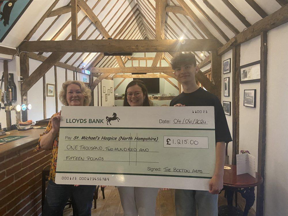 3 people holding cheque in the bolton arms